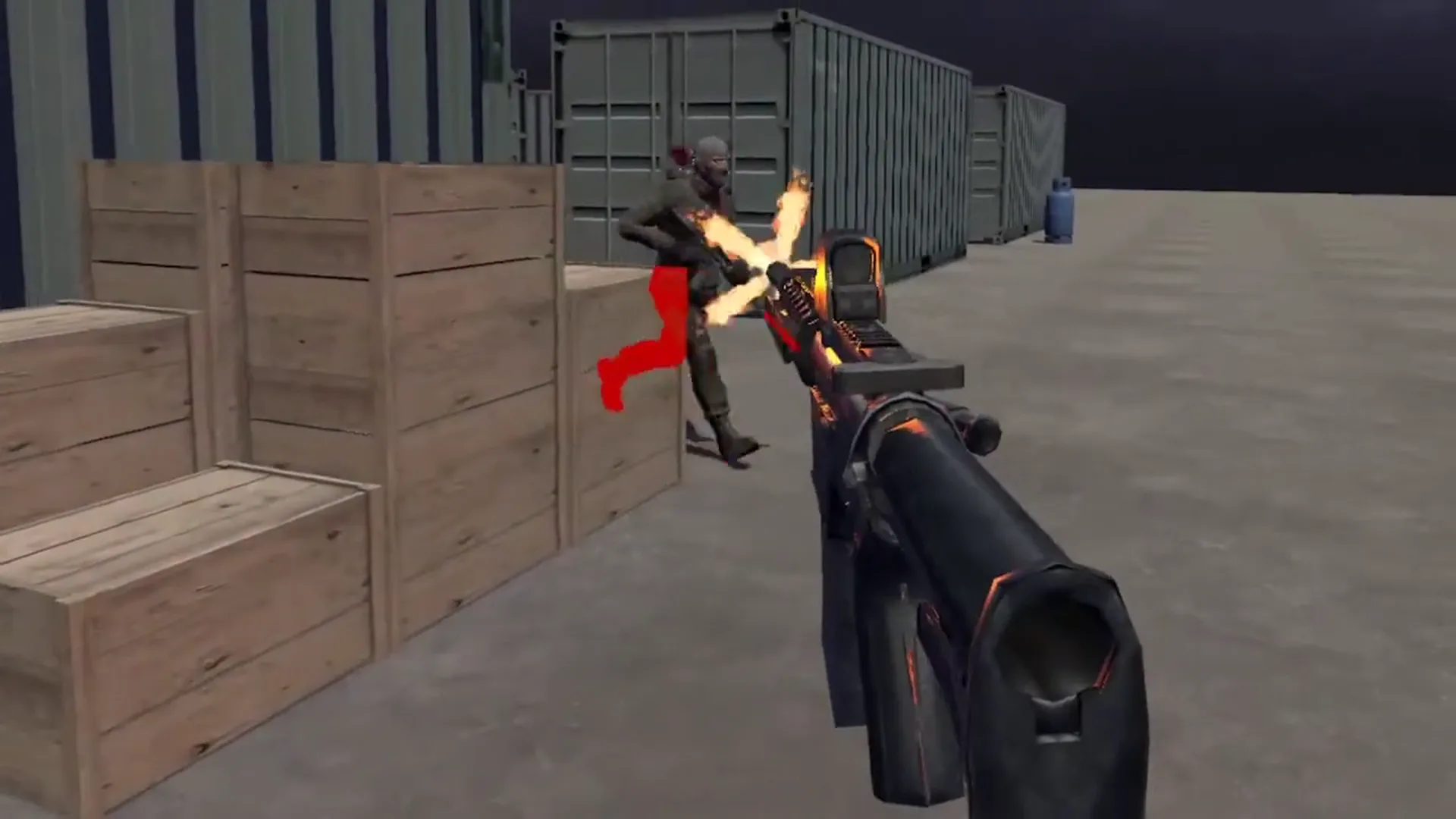 Player firing at a running enemy, hitting them in an industrial environment with crates, containers, and an explosive barrel in the distance.